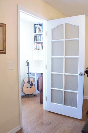 A room with a white door, a guitar, a chair, and a bookshelf. - Child-Friendly Retreat Near Charleston (Hanahan)