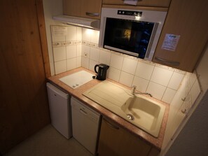 A compact kitchen with a dishwasher, a sink, a kettle, and an oven. - Quiet apartment with terrace - 4 guests (Villarodin-Bourget)