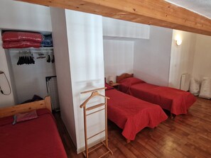 A bedroom with two single beds, a wooden wardrobe, and a hanging clothes rack. - 3-room apartment, south balcony - 6 guests (Modane)