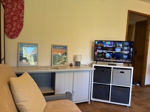 A living room with a television, two framed pictures, a lamp, and a sofa. - Cozy studio - 4 guests, slopeside (Les Carroz d'Arâches)