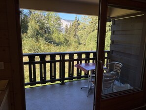 A balcony with a wooden railing, a small table, and two chairs. - Cozy studio - 4 guests, slopeside (Les Carroz d'Arâches)