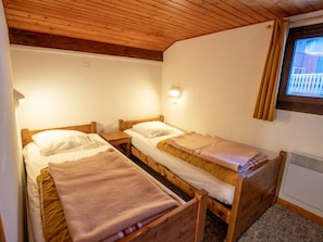 Ein Zimmer mit zwei Holzbettklappen, einer Wandleuchte und einem Fenster mit Vorhängen.