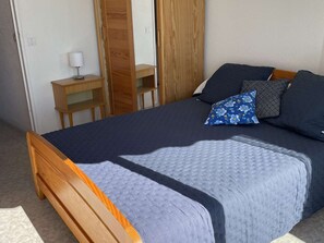 A bedroom with a bed, a nightstand, a lamp, and a wardrobe. - Duplex with parking - 6 guests in quiet area (Le Grau-du-Roi)