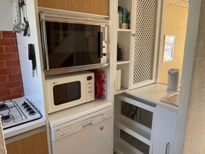 A compact kitchen with a stove, microwave, and a small refrigerator. - Duplex with parking - 6 guests in quiet area (Le Grau-du-Roi)