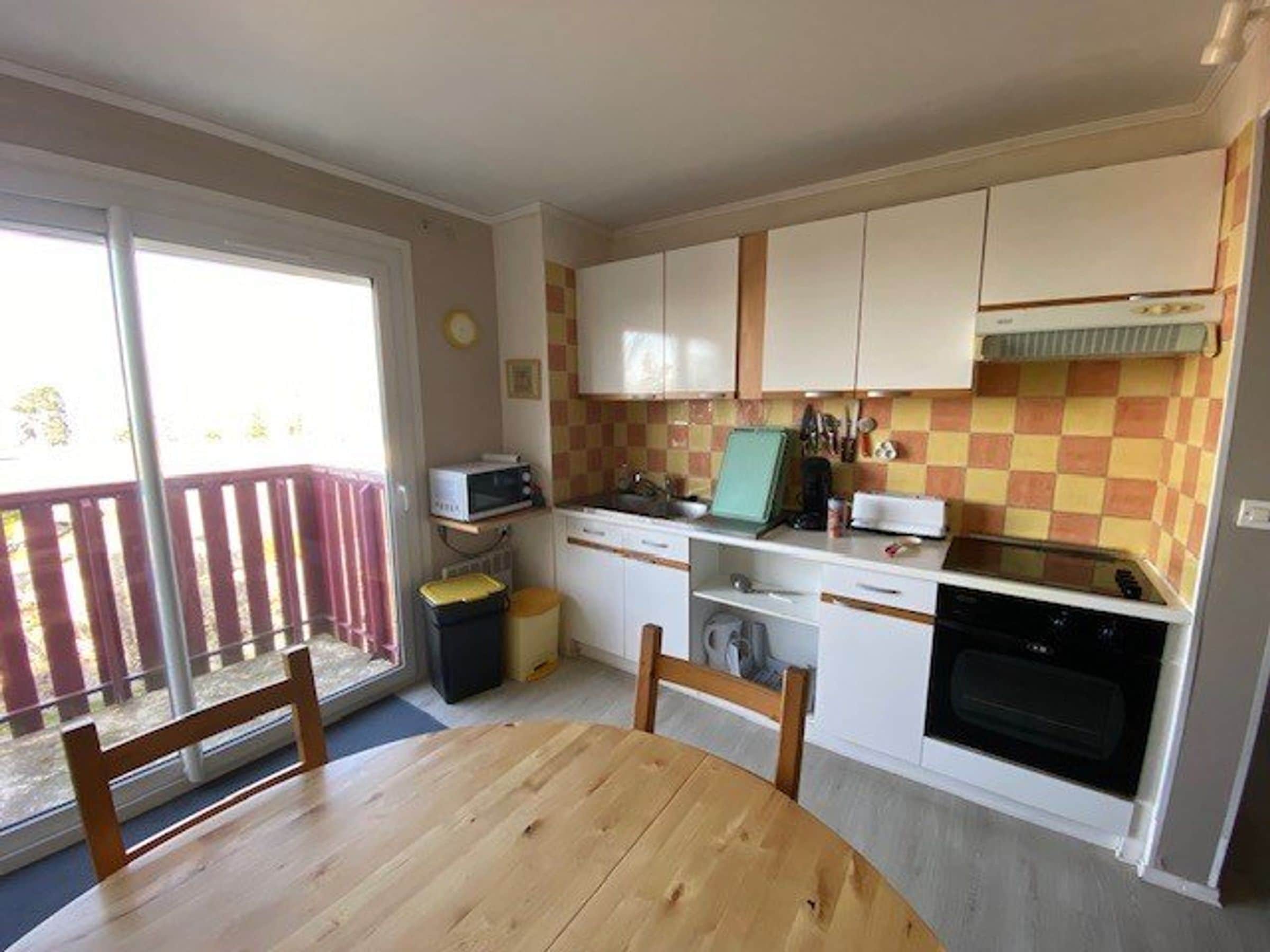 A compact kitchen with a dining table, a microwave, a toaster, and a stove.