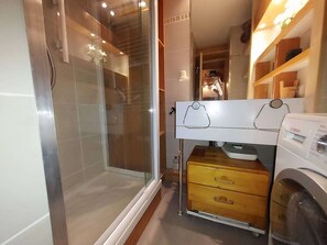 A compact bathroom with a glass shower enclosure, a Bosch washing machine, and a wooden cabinet. - Bright studio at the foot of the slopes (Valmorel)