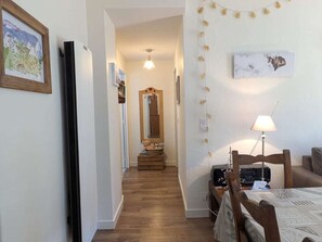 Ein enger Flur, der in ein Schlafzimmer mit einem Bett, einer Lampe und einer Kommode führt.