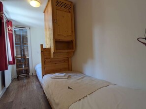 Ein Einzelbett mit Holz Kopfteil und einem kleinen Holzschrank darüber.