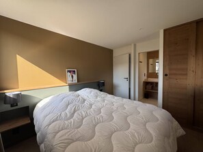 Una camera da letto con un letto, un comodino, una lampada, un quadro appeso al muro e una porta in legno.
