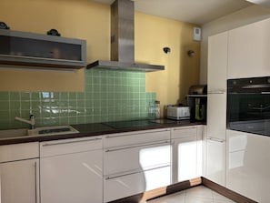 A kitchen with white cabinets, a green tiled backsplash, a stainless steel range hood, a built-in oven, and a toaster. - Apartment with wifi - 6 guests, mountain view (Villard-de-Lans)