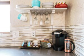 Une cuisine équipée d’une machine à café, d’une bouilloire et d’une tasse sur le plan de travail.