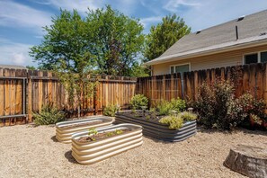 A backyard with a wooden fence, a house, and raised garden beds. - #StayInMyDistrict 2Bed DogsOk Spa Monthly Rental (Boise)
