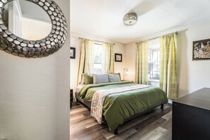 Une chambre à coucher avec un lit, un miroir rond et une fenêtre avec des rideaux.