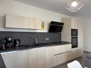 Eine moderne Küche mit schwarzem Arbeitsplatz, Edelstahlgeräten und hellen Holzschränken.