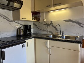 A compact kitchen with a marble backsplash, a stainless steel sink, and a coffee maker. - Cozy studio in the heart of the village - 2 guests (Villard-de-Lans)