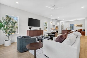 A modern living room with a sofa, armchair, and a dining area with a table and chairs. - Garage, Near Downtown Broadway + Rooftop with Dining Table (Nashville)