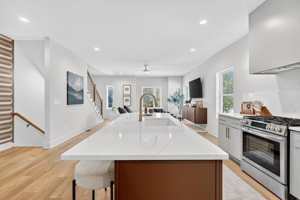 A modern kitchen with a central island, built-in appliances, and a view to the living area. - Garage, Near Downtown Broadway + Rooftop with Dining Table (Nashville)