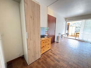 A room with a wooden wardrobe, a small desk with a television, and a sliding glass door leading to an outdoor area. - Quiet studio with parking - 2 guests (Bandol)
