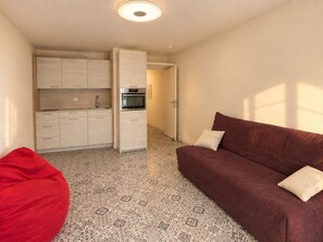 A compact living space with a kitchenette, a sofa, and a red bean bag. - Ideal apartment in Six-Fours - 4 guests (Six-Fours-les-Plages)