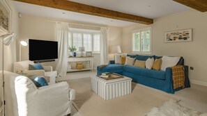 A living room with a blue sofa, white armchairs, a coffee table, and a flat-screen TV. - Rowan House - Bourton-on-the-Water, Sleeps 7 (Bourton-on-the-Water)