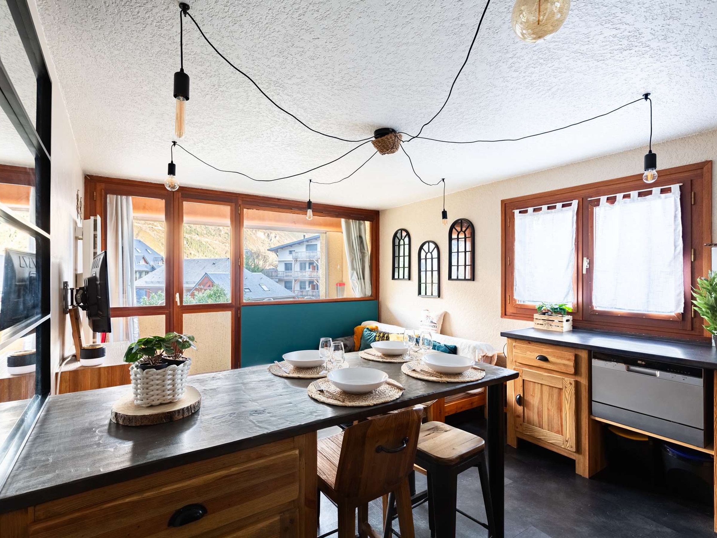 A kitchen with a wooden table, chairs, and a view of the outside.