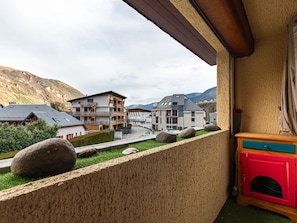 A balcony with a view of a mountain, a red cabinet, and a grassy area with rocks. - Apartment mountain view - 4 guests (Saint-Lary-Soulan)