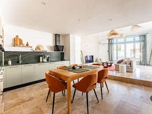 A modern kitchen with a dining area, a sofa, and a large window. - Villa with pool and AC in village center - 6 guests (Sainte-Marie-de-Ré)
