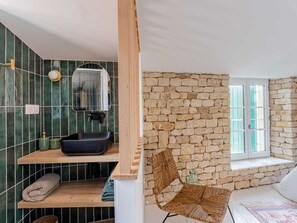 A bathroom with a black basin, a wooden shelf, a woven chair, and a stone wall. - Villa with pool and AC in village center - 6 guests (Sainte-Marie-de-Ré)