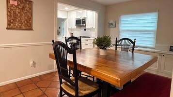 Un coin repas avec une table en bois, quatre chaises, un banc rouge et une plante en pot.