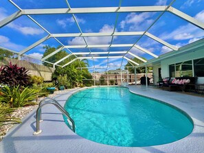 Une piscine couverte avec une structure en métal, entourée de plantes et d’une clôture en bois.