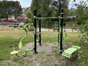 An outdoor exercise area with various fitness equipment, a bench, and a playground structure. - Chalet with air conditioning - 6 guests (Saint-Maime)