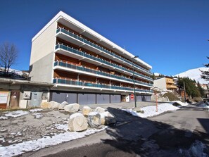 A multi-story hotel with balconies, a snow-covered ground, and a clear sky. - Cozy apartment mountain view - 4 guests (Chamrousse)