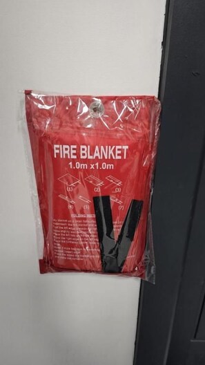 A red fire blanket package hanging on a wall. - Single & Double rooms in Stafford (Stafford)