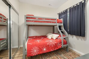 A bunk bed room with a red and white patterned bedspread, a gray metal ladder, and a window with dark curtains. - Modern Mountain Escape MH404 |Hot Tub |Pool | Golf (Eden)