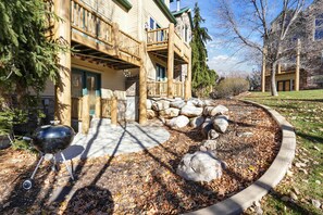 A lodge with a stone facade, wooden deck, and a barbecue grill in the foreground. - Modern Mountain Escape MH404 |Hot Tub |Pool | Golf (Eden)