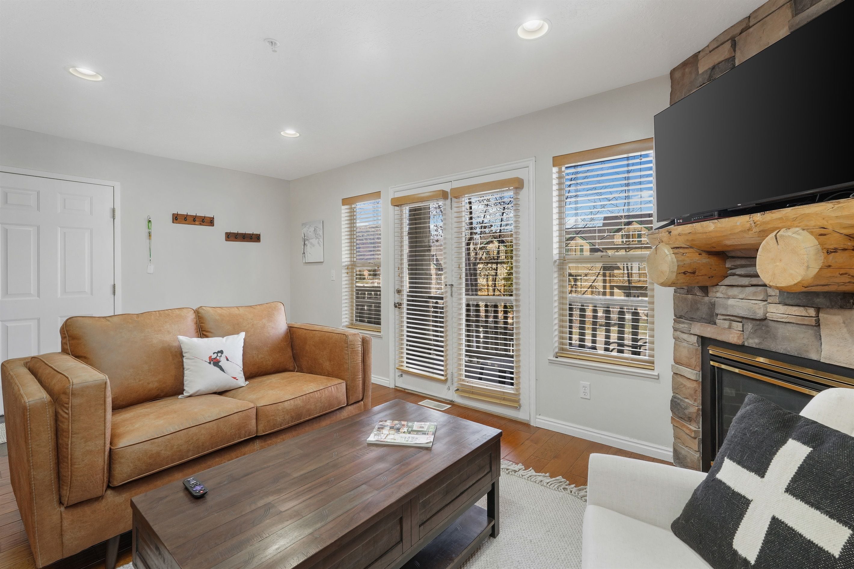 A living room with a brown leather sofa, a coffee table, and a fireplace with a stone surround.