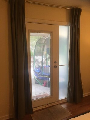 En skjutdörr i glas som vetter mot ett utomhusområde, med bland annat en studsmatta och en täckt uteplats.