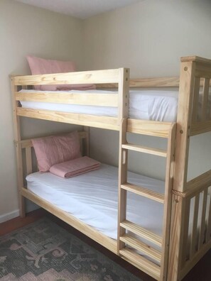 A bunk bed with a wooden frame, a lower bunk with a mattress and pillows, and a top bunk with a mattress and a pillow. - Family-Friendly Retreat Near Charleston (Hanahan)