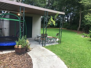 A covered patio area with a trampoline, seating, and potted plants. - Family-Friendly Retreat Near Charleston (Hanahan)