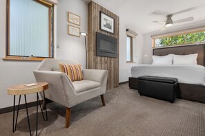 A hotel room with a bed, a sofa, a small table, and a TV mounted on the wall. - Downtown | On Bus Route | Garage Gear Storage | Pet Friendly (Steamboat Springs)