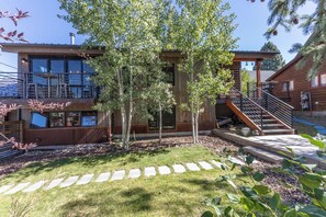 A modern building with a wooden facade, a visible staircase, and a stone pathway leading to the entrance. - Downtown | On Bus Route | Garage Gear Storage | Pet Friendly (Steamboat Springs)