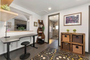 Eine moderne Küche mit schwarzem Arbeitsplatz, einem Barhocker, einem Holzbodenregal und einem gemusterten Teppich.