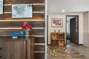 A reception area with a wooden wall, a framed map, a vase with flowers, a blue bowl, and wicker baskets. - Downtown | On Bus Route | Garage Gear Storage | Pet Friendly (Steamboat Springs)