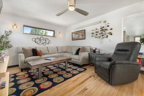 A living room with a sofa, a coffee table, a chair, a ceiling fan, and a patterned rug. - Downtown | On Bus Route | Garage Gear Storage | Pet Friendly (Steamboat Springs)