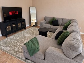 A living room with a sectional sofa, a coffee table, a flat-screen TV, and a cabinet. - Beautiful 3-bedroom 2 Bath house with AC in charming El Paso (El Paso)