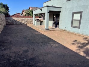 Ein Wohnhaus mit Steinmauer, überdachter Terrasse und Schotterweg.