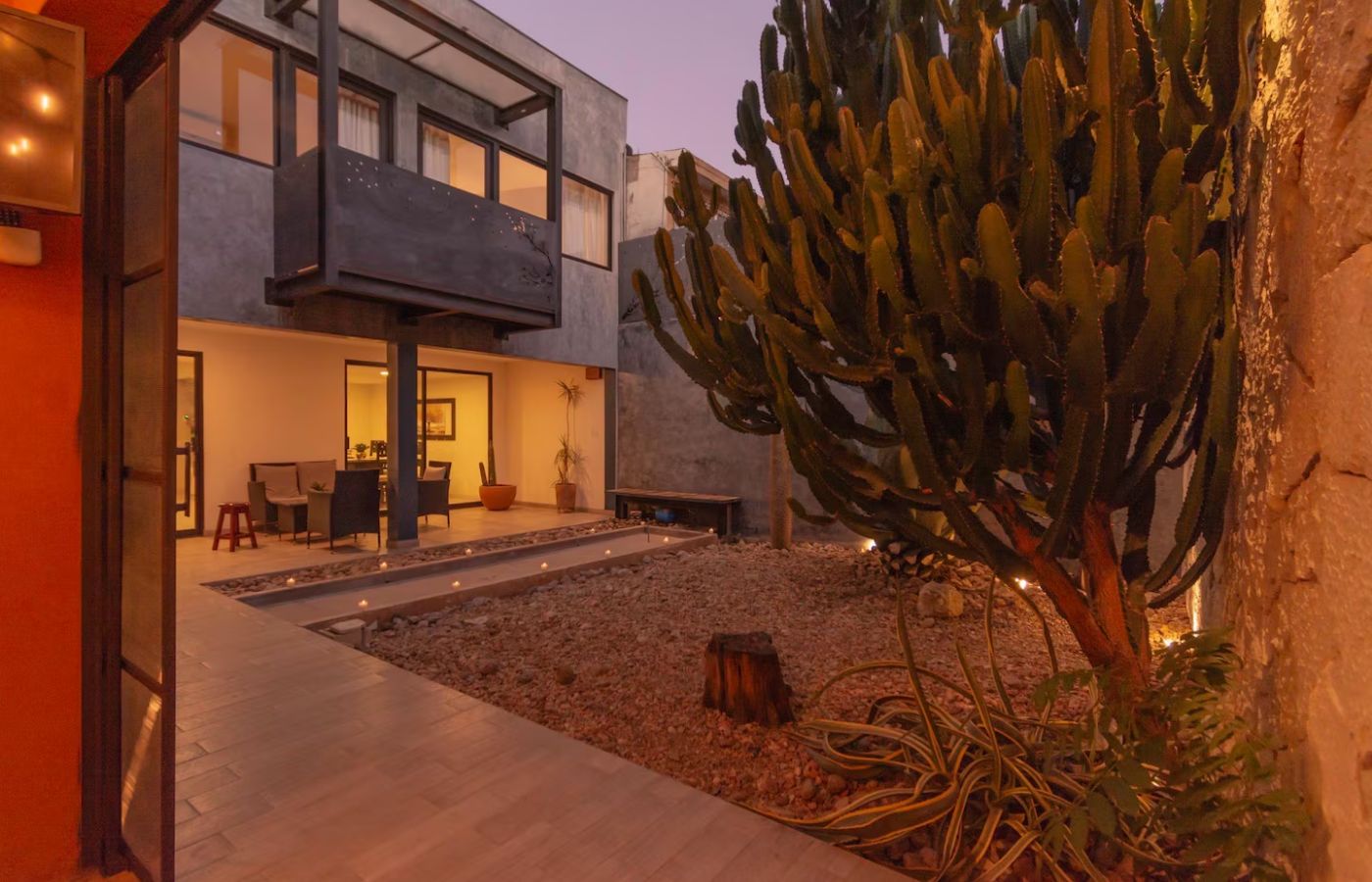 Een modern huis met een terras, een cactus en een eethoek.