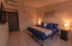 A hotel room with a bed, bedside lamps, a wardrobe, and a television. - Casa Marmorata | Residence with Air Conditioning and Parking (Oaxaca de Juárez)