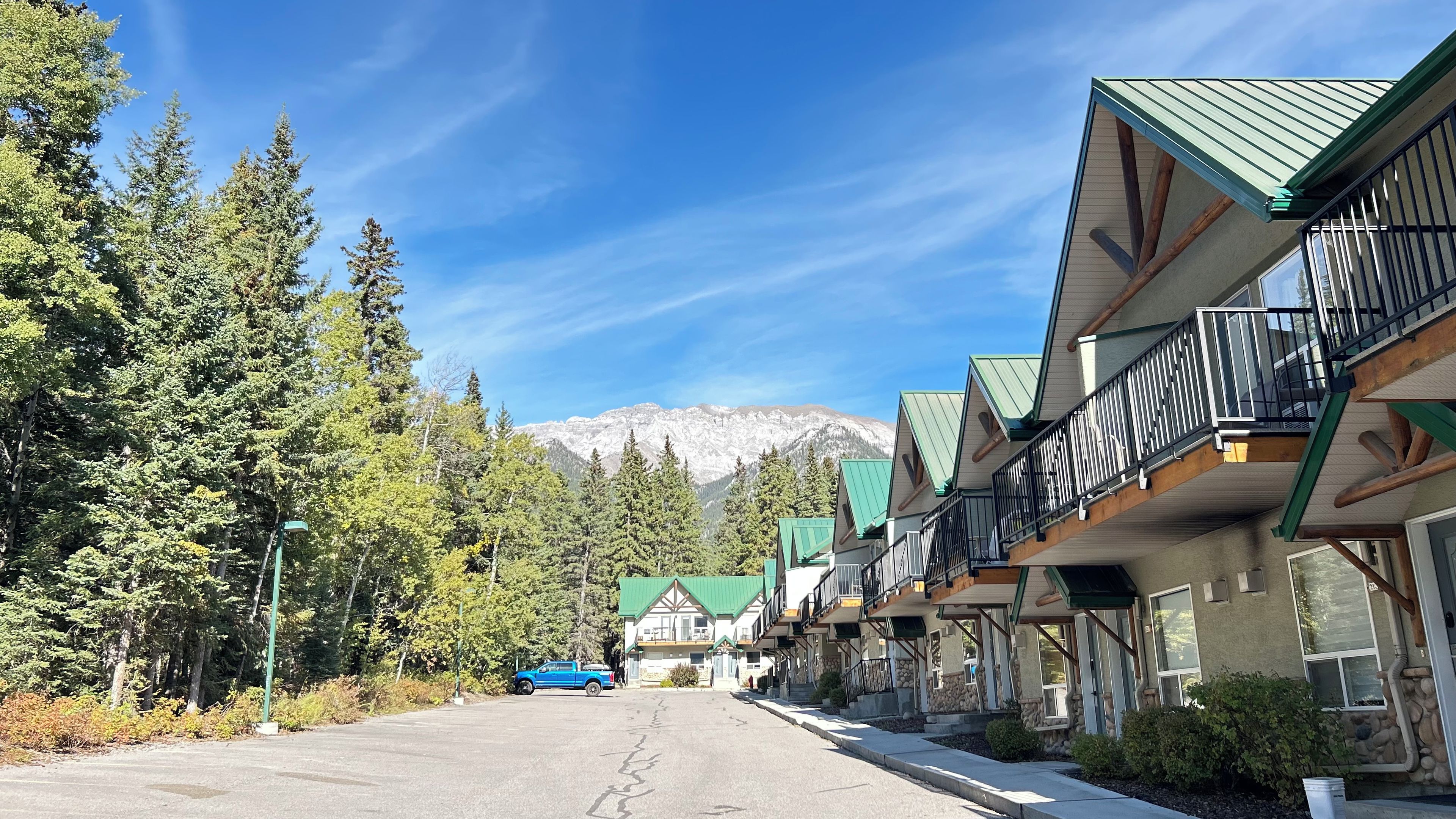 A row of buildings with balconies, a clear sky, and a mountain in the background.