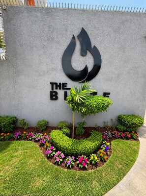 A building facade with a large flame logo and the text 'THE BLUE HOUSE' below it. - Spacious 2-bedroom apartment in serene Kingston with AC , pool , and gym access (Kingston)